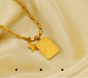 Dettaglio della collana in acciaio al titanio oro con ciondolo a scacchi e stella su raso