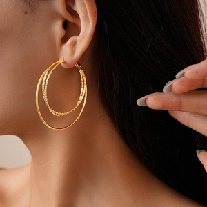 Close-up of 18k gold-plated triple-layer hoop earrings with textured twist and polished finish