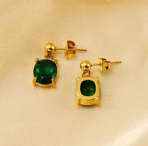 Détail des boucles d'oreilles ovales en zircon vert avec sertissage à griffes dorées