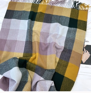 Close-up of yellow and purple plaid pattern and soft fringe tassels on warm scarf
