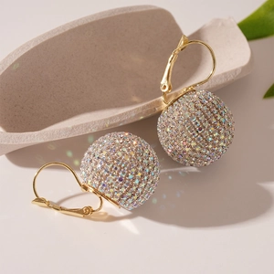 Détail macro de boucles d'oreilles dorées avec sphères de cristaux multicolores
