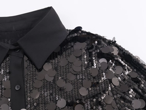 Detail of black sequined shirt showing large round sequins, classic collar and buttons