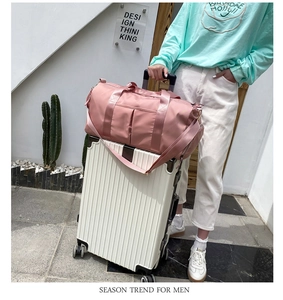 Pink travel bag with luggage strap sleeve shown attached to a white suitcase handle