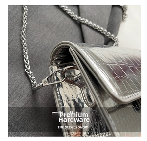 Detail of silver crocodile pattern leather handbag showing premium metal chain and lobster clasp