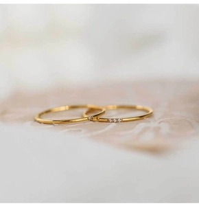 Macro detail of minimalist gold rings with fine zircon stones on polished steel