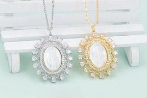 Detail of gold and silver Virgin Mary pendants with white shell and zircon accents