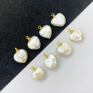 Set of heart-shaped white baroque freshwater pearls with golden metal loops on a split background