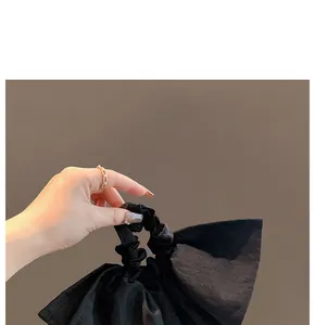 Close-up of a large black fabric bow scrunchie with a soft matte texture for hair