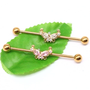 Detail view of gold industrial barbell featuring crystal butterfly on green leaf