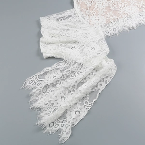 Close-up of white floral lace fabric with delicate hollow patterns and eyelash trim detail