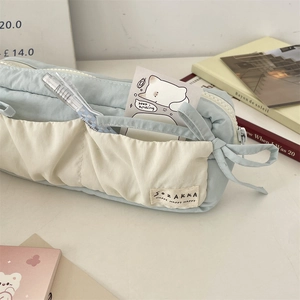 Detail of blue canvas stationery bag with ribbon bow and multiple storage pockets