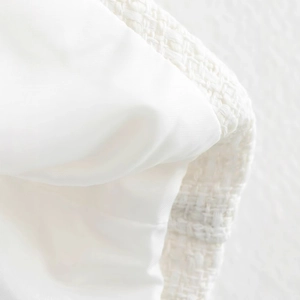 Close-up of elegant white tweed cloak jacket with detailed weaving and smooth lining