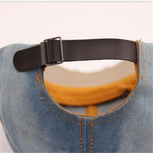 Macro shot of light blue denim baseball cap featuring an adjustable black leather strap