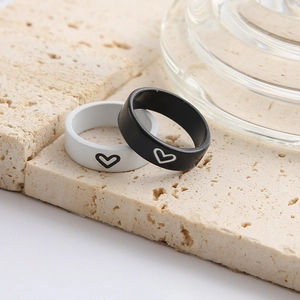 Minimalist black and white heart couple rings with matte finish on stone surface