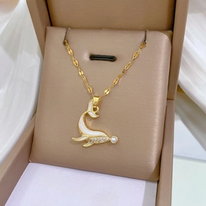 Close-up of golden dolphin pendant with white enamel, pearls and zircon in a jewelry box
