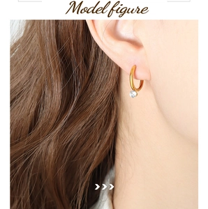 Close-up of elegant gold hoop earrings with sparkling round cubic zirconia pendant on ear