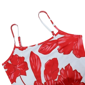Close-up of red floral pattern and thin straps on a white vacation style summer dress
