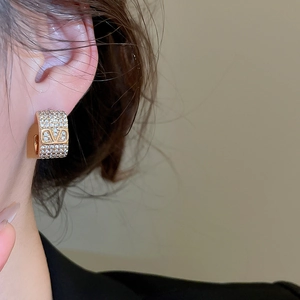 Macro shot of a gold-plated V-shaped stud earring with shimmering pavé crystals on a model