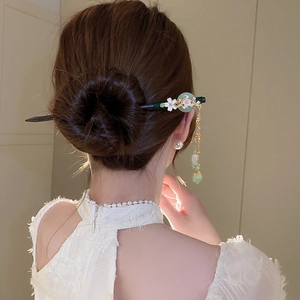 Detail of vintage flower hair stick with pearl tassels styled in a classic bun