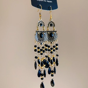 Macro shot of vintage bohemian earrings with gold leaves and black beaded tassels