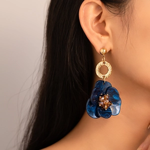 Détail d'un mannequin portant des boucles d'oreilles fleurs en résine bleue vintage