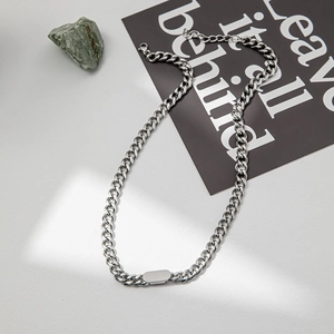 Flat lay of a silver Cuban link necklace featuring a polished rectangular metal plate