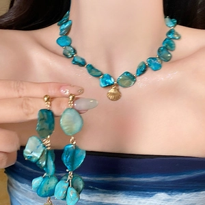 Blue beaded necklace and earring set featuring a gold shell pendant for beach vacations