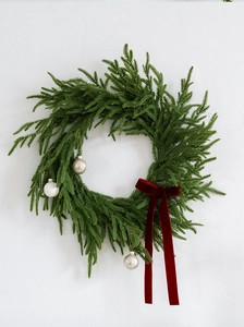 Close-up of green cedar wreath featuring three silver balls and a red velvet bow ornament