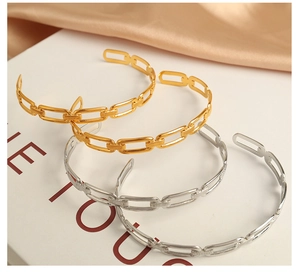 Detailed view of gold and silver chain link bangles on champagne silk fabric background