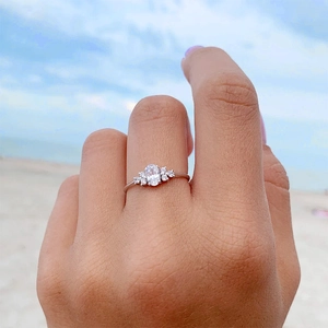 Elegante zilveren ring met ovale zirkoon en zijstenen, gedragen tegen een strandachtergrond