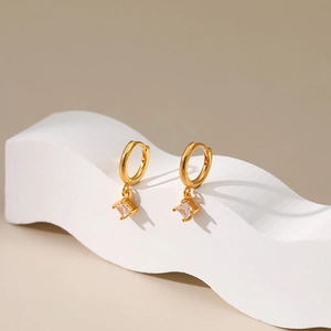 Close-up of gold plated hoop earrings featuring square cut zircon in four-prong setting