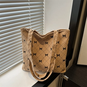 Beige corduroy tote bag featuring black bow patterns and quilted diamond stitching
