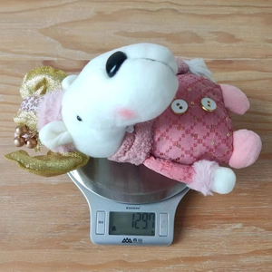 Pink plush reindeer decoration with sequins being weighed on a digital scale