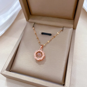 Rose gold flower necklace with pink gemstone pendant in a beige jewelry box