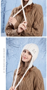 Detail view of white knitted earflap hat with long ties and x-stitch decoration