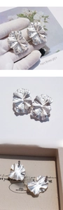 Détail macro de boucles d'oreilles fleurs argentées avec texture de pétale brossée