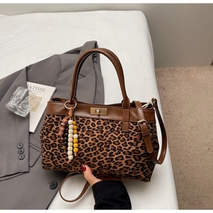 Dettaglio borsa leopardata con finiture in pelle marrone e ciondolo in perline di legno