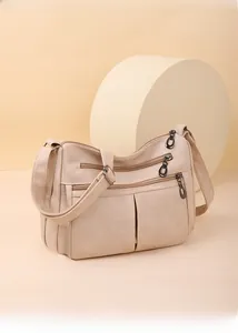 Detailed view of beige multi-zipper shoulder bag with soft texture and metallic hardware