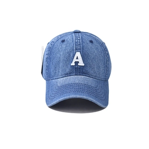 Dettaglio della lettera A bianca ricamata su un berretto da baseball in denim blu lavato