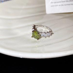 Macro shot of silver ring with green zircon center stone and side rectangular accents