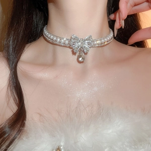 Macro detail of luxury bowknot choker with crystals, pearls, and a teardrop pendant