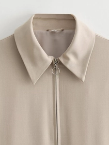 Detail of the ring zipper and lapel collar on this beige casual baseball jacket