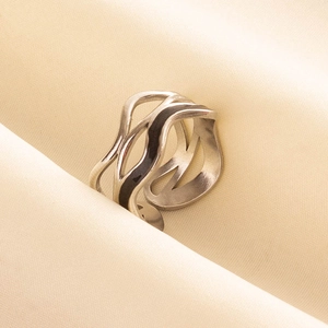 Detailed close-up of layered wavy hollow silver stainless steel ring on beige silk