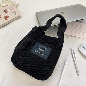 Détail d'un mini sac seau en velours côtelé noir posé sur un bureau de travail