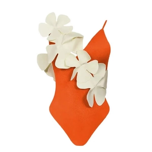 Detail of orange one-piece swimsuit featuring a large white 3D floral accent on the chest