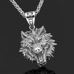 Macro detail of silver wolf head pendant with intricate viking engraving and metal chain