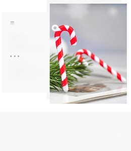 Close-up of red and white spiral candy cane ornaments on a festive pine tree branch