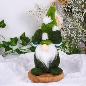 Close-up of green Christmas gnome plush on a wooden base with festive pine decorations