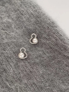 Macro detail of silver needle gourd earrings with sparkling zircons and pearls