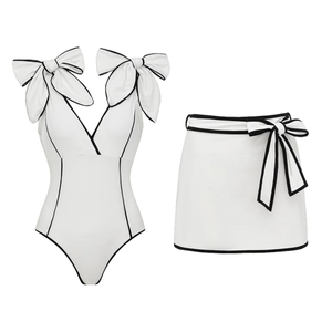 White one-piece swimsuit with black bow accents and matching mini skirt set